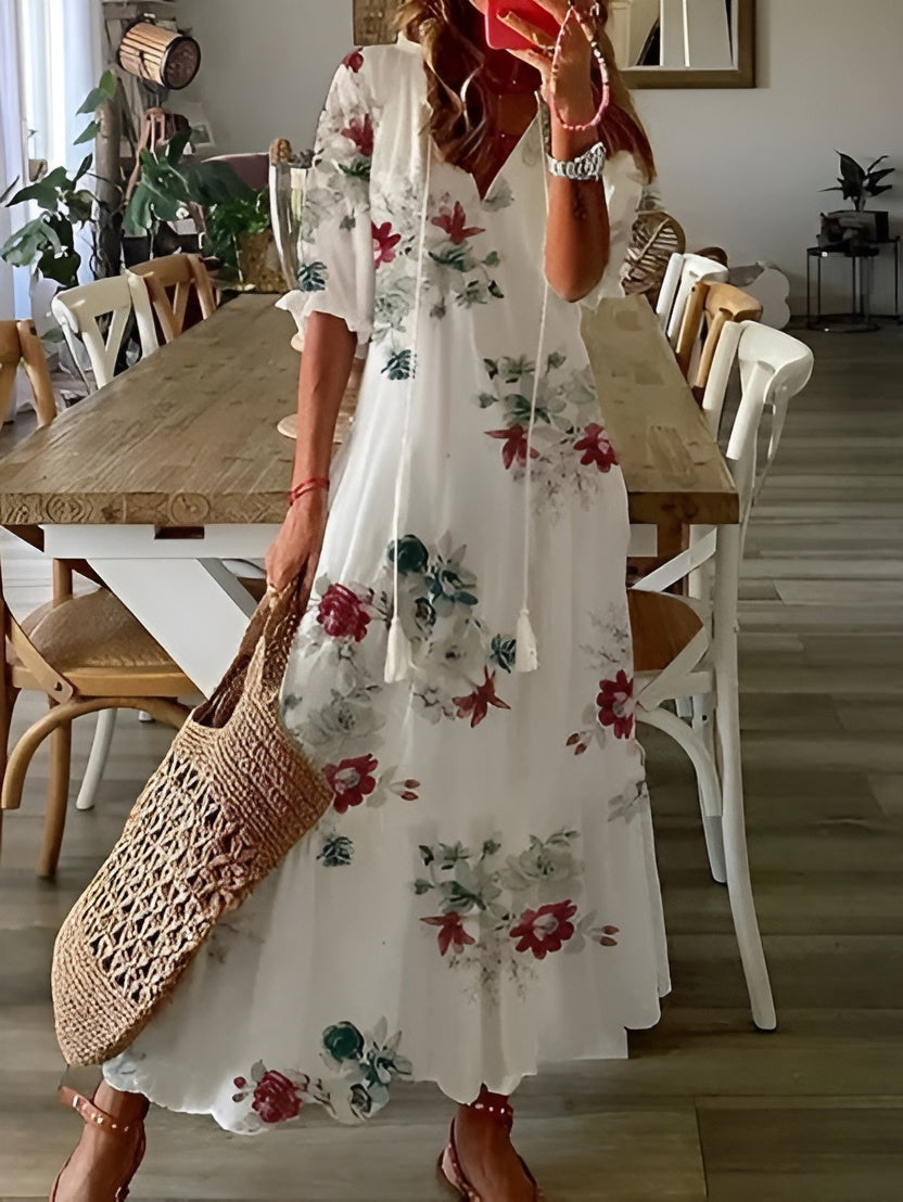 Woman in a floral dress holding a woven bag in a dining room.