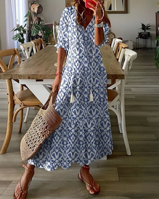 Woman wearing a blue patterned dress holding a woven bag on a white background