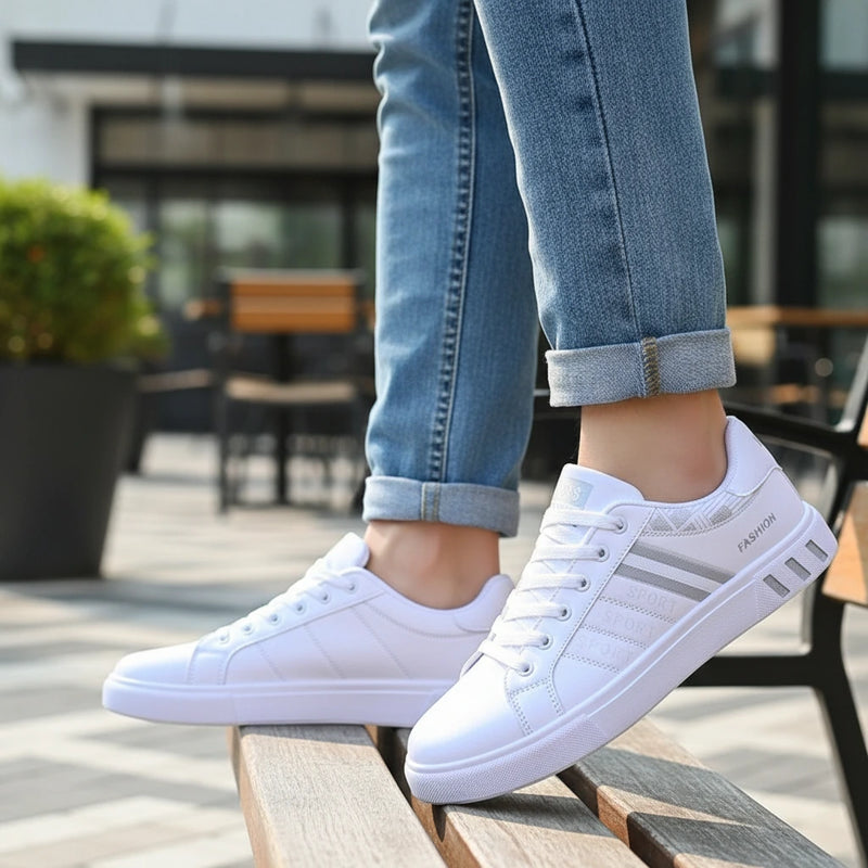 White sneakers with gray stripes worn by a person sitting on a wooden bench.
